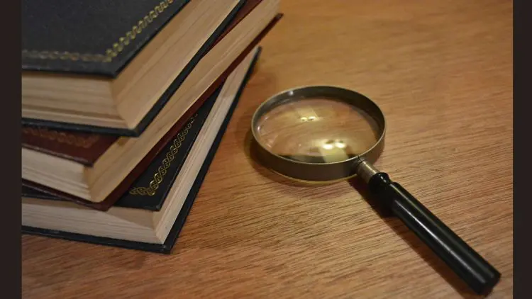 Stack of books and a magnifying glass - mystery